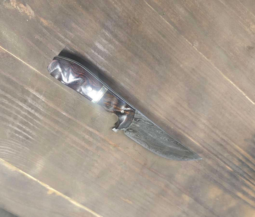 Alabama Damascus knife with desert ironwood and red linen Micarta handle, brass and nickel dividers and white G10 inlay — angled view